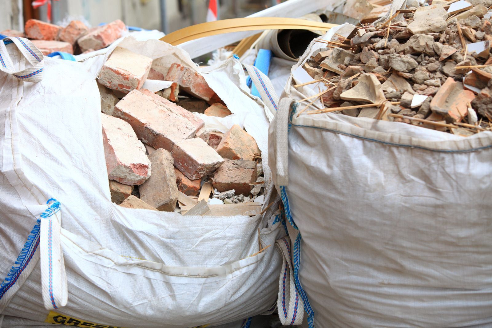 Two open white bags filled with construction debris: bricks and rubble.