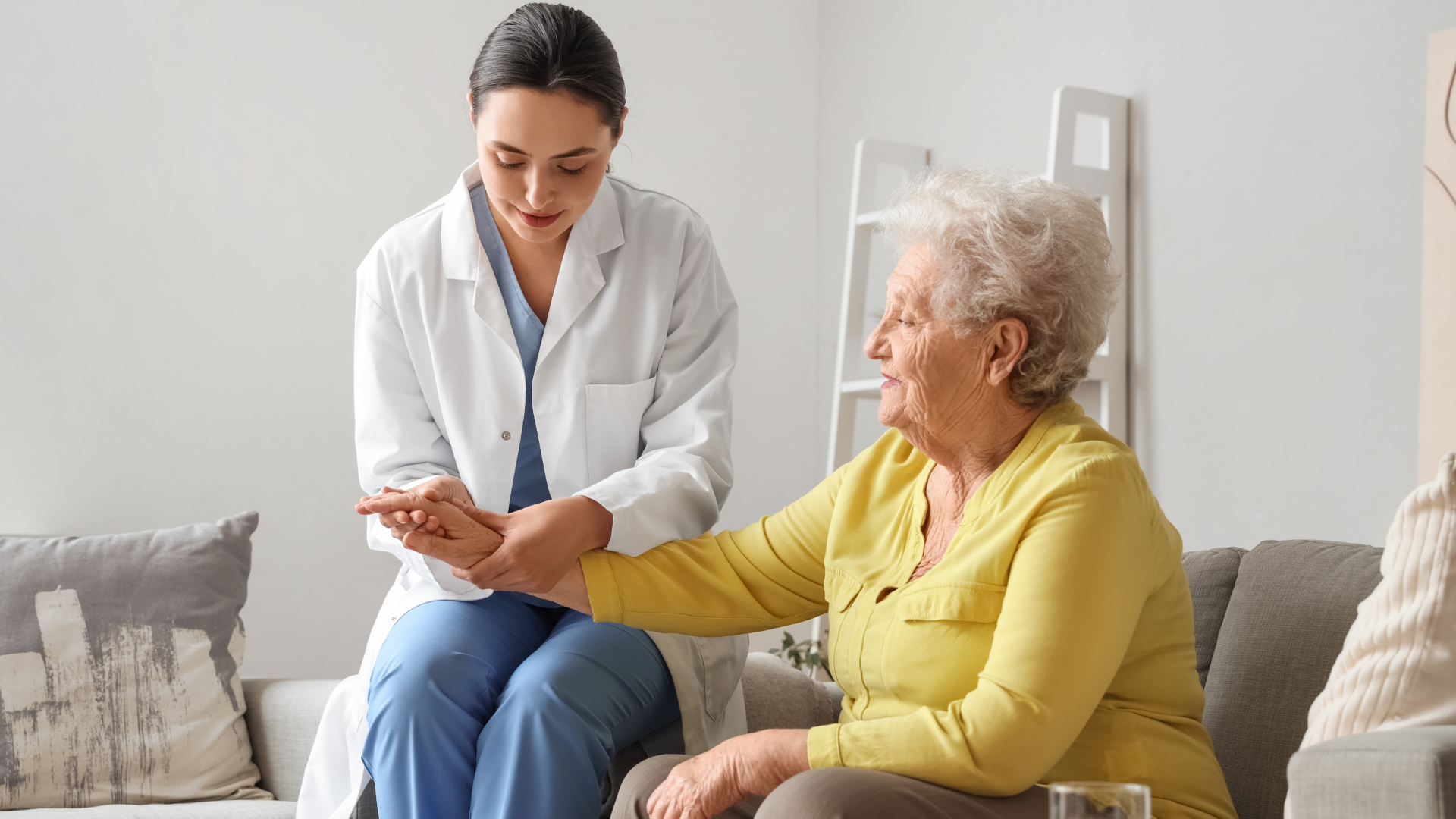 Doctor consulting with an elderly patient on a couch in a bright living room