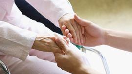 Hands gently holding and comforting another hand in a bright, clinical setting