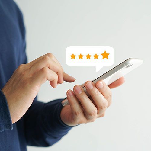 A person is holding a cell phone with a speech bubble that says five stars.