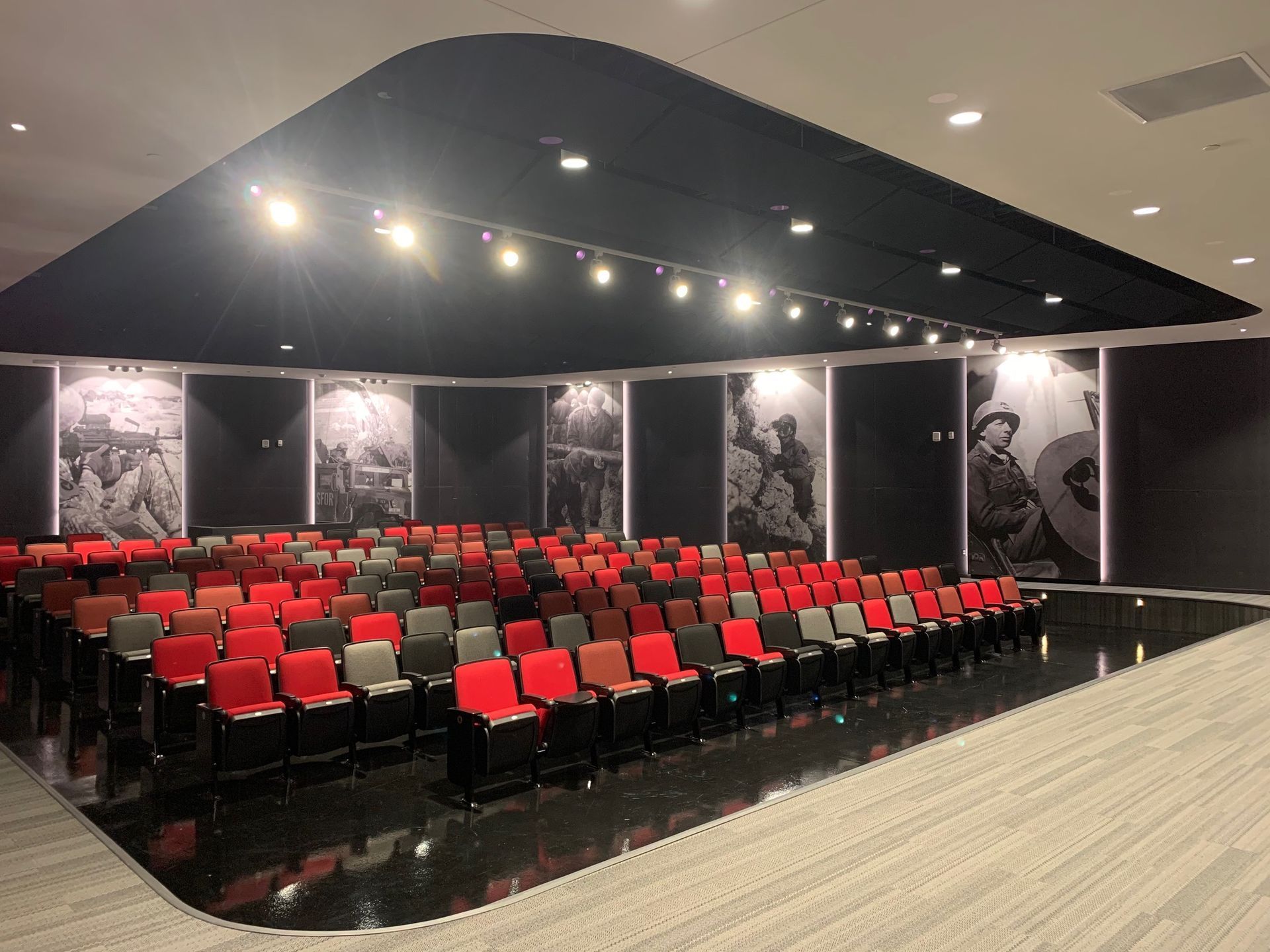 A large auditorium with rows of red and gray chairs