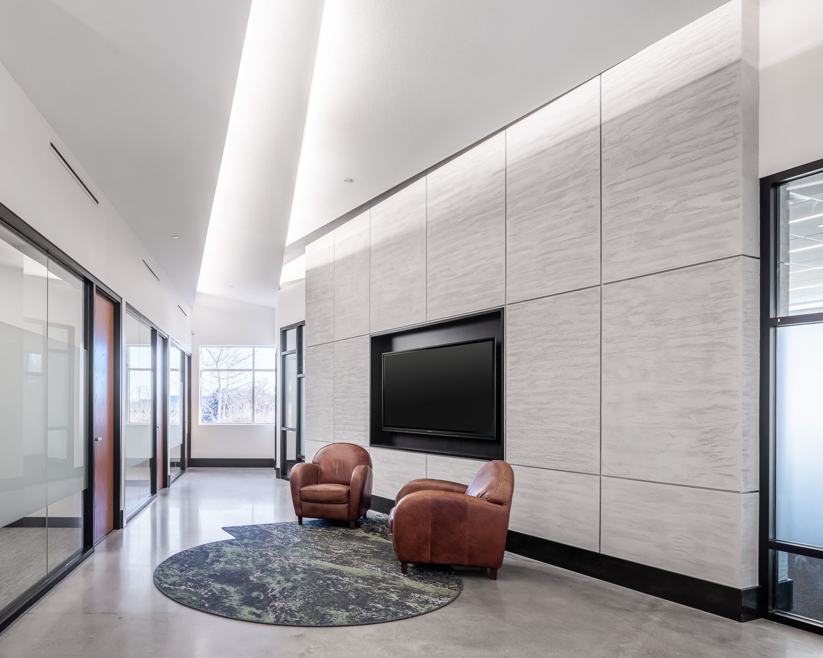 A Hallway With Two Chairs and a Flat Screen Tv on the Wall