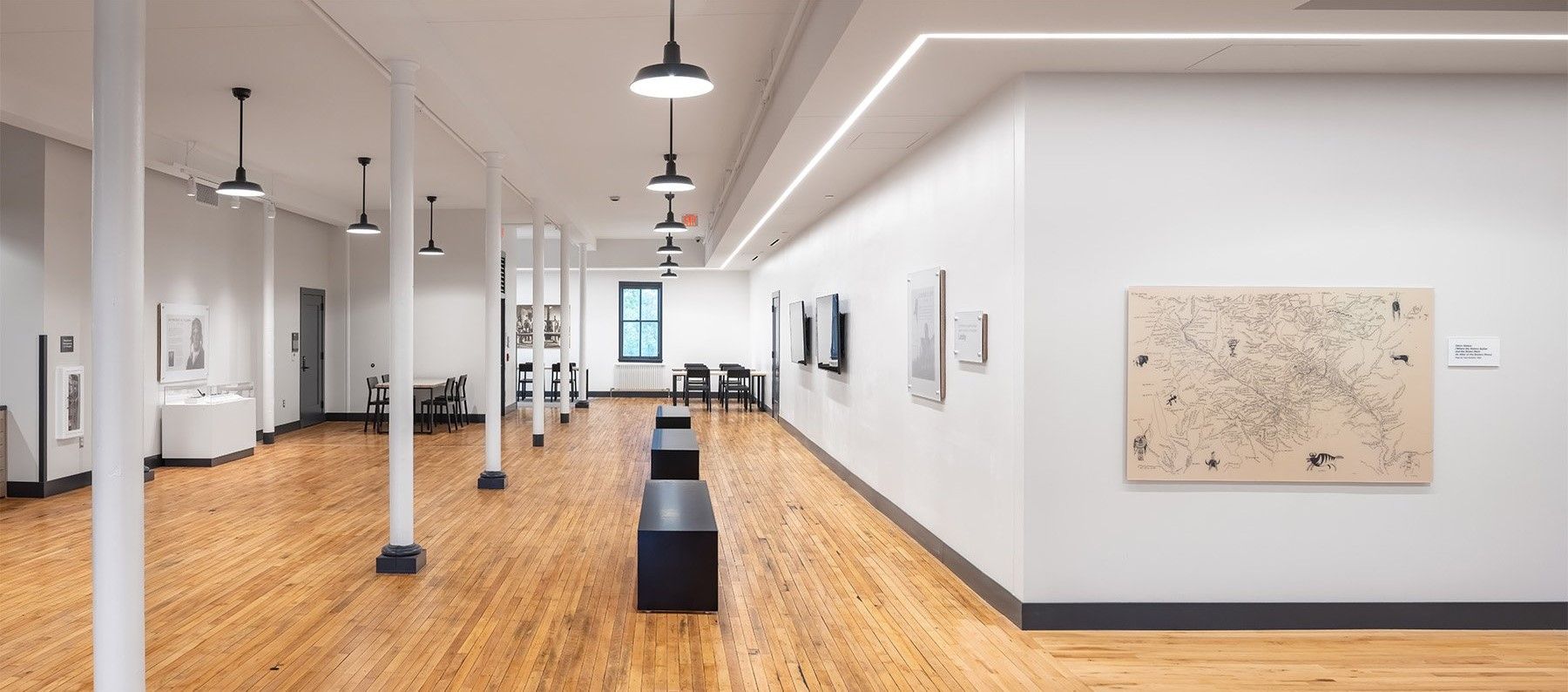 A long hallway with wooden floors and a painting on the wall.