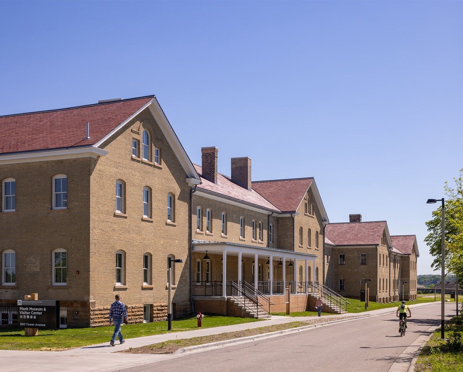A man walks down a sidewalk in front of a row of brick buildings