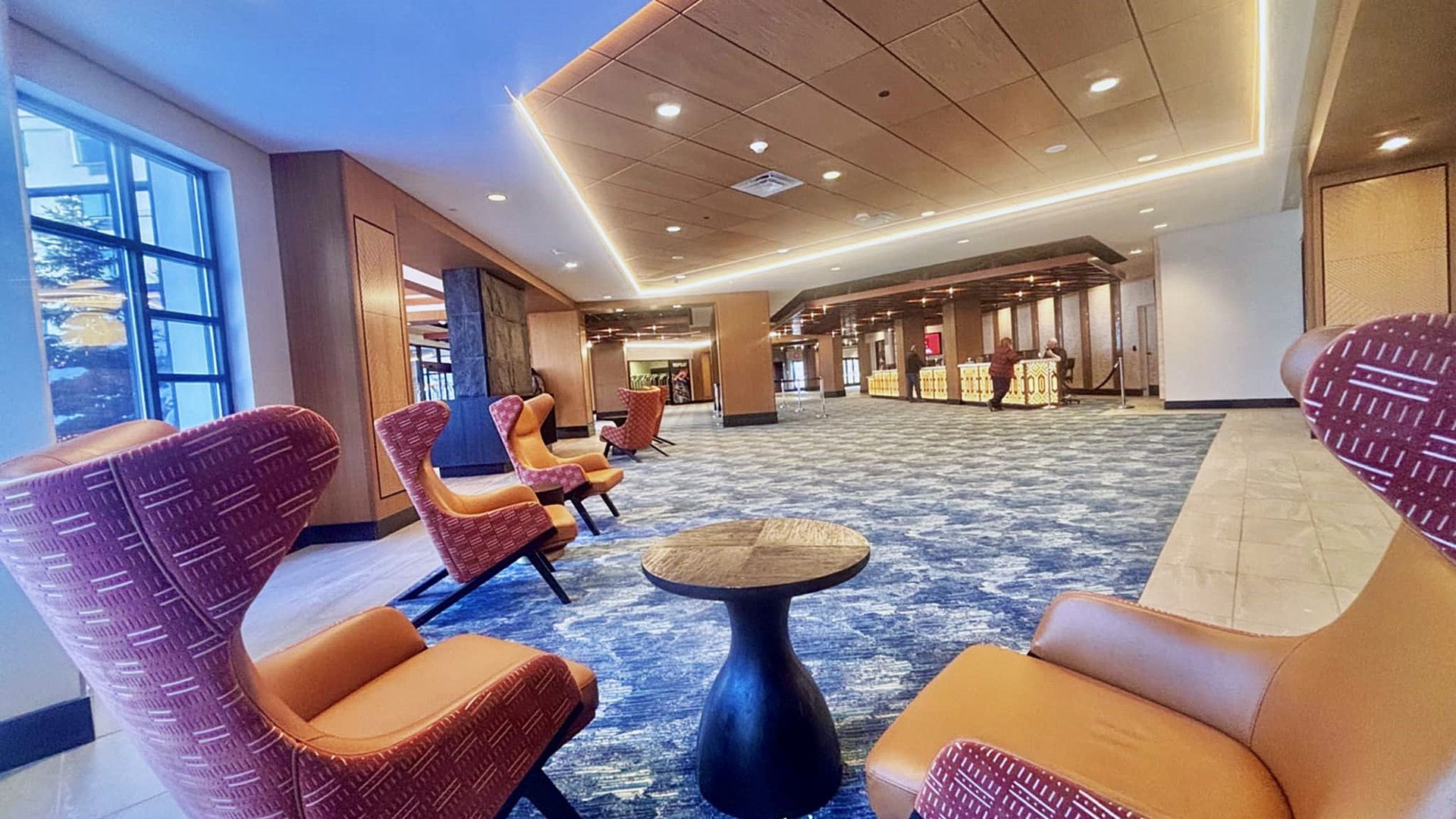 There are many chairs and a table in the lobby of a hotel.