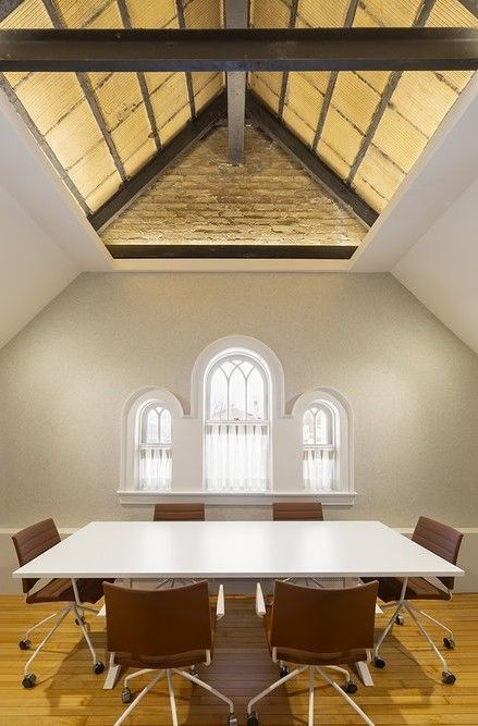 A conference room with a table and chairs and a brick ceiling.