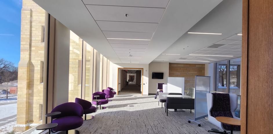 A long hallway in a building with purple chairs and tables.