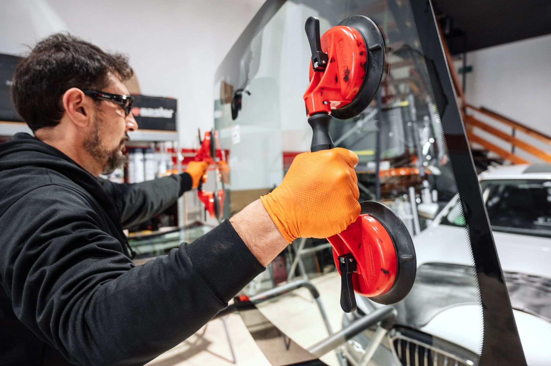 A person using a red suction cup tool install a large glass pane. A person using a red suction cup tool install a large glass pane.