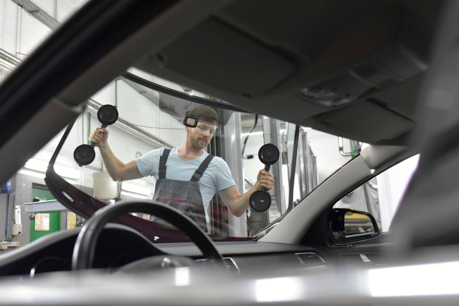 Worker installing a windshield in a car at an auto repair shop. Worker installing a windshield in a car at an auto repair shop.