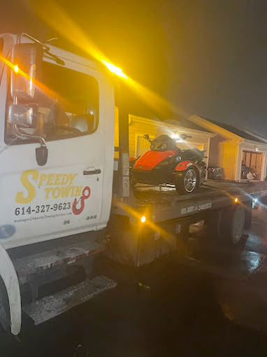 A tow truck is carrying a motorcycle on the back of it.
