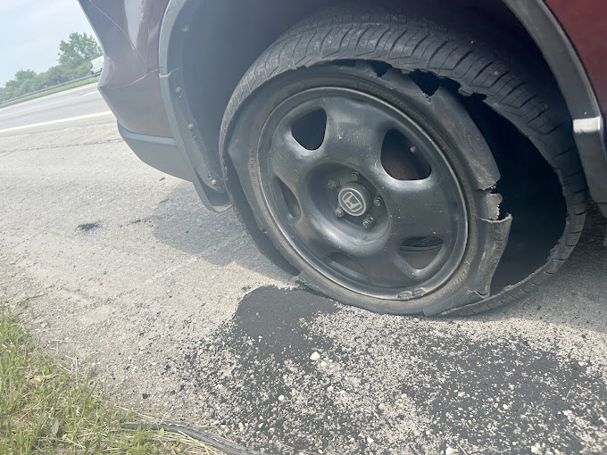 A car with a flat tire on the side of the road.