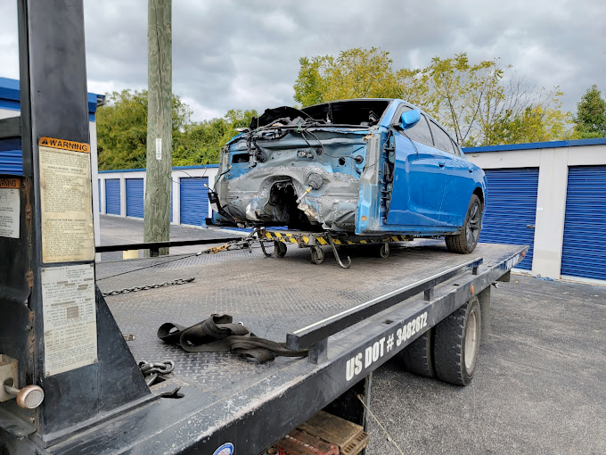 A blue car is sitting on top of a tow truck.