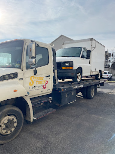 A tow truck is towing a white van and a white truck.