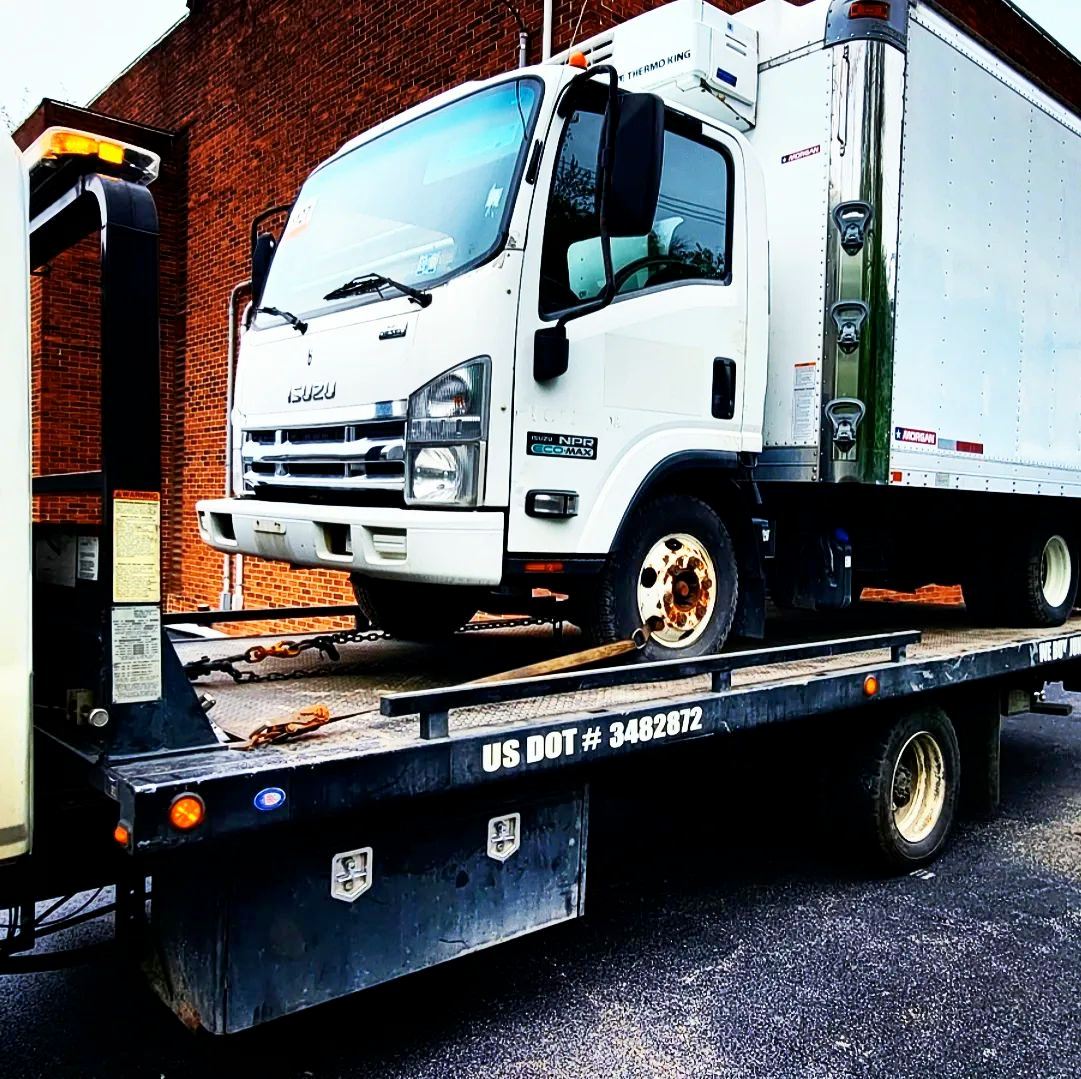 A white truck is sitting on top of a tow truck.