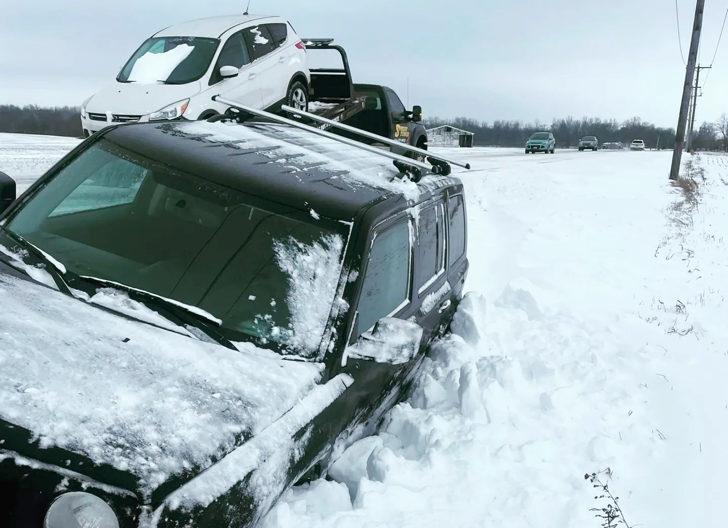 A car is stuck in the snow on the side of the road.