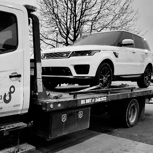 A white range rover sport is being towed by a tow truck.