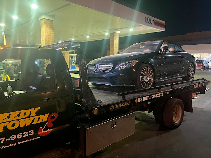 A black car is sitting on top of a tow truck.