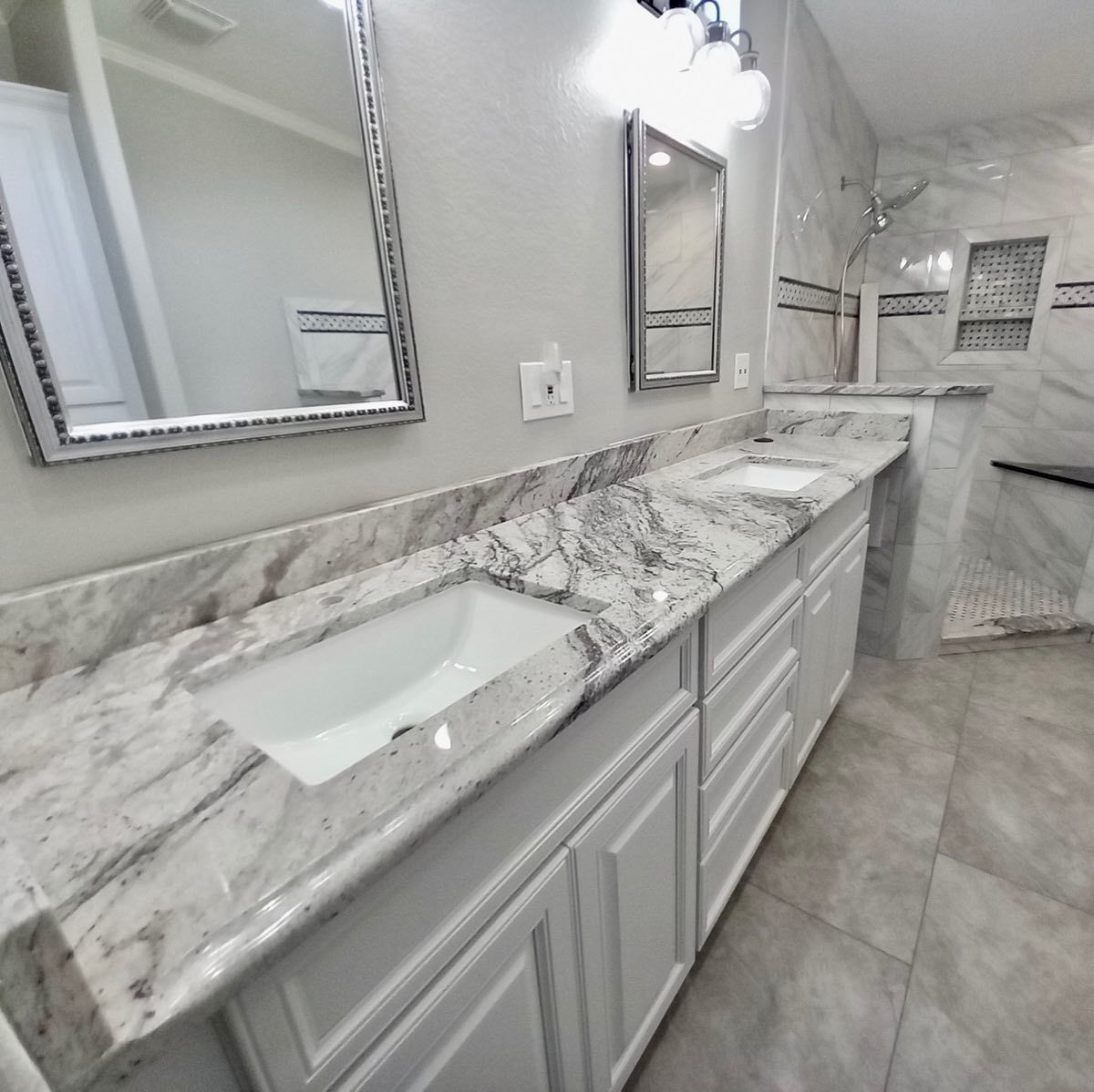 Bathroom with double vanity, white cabinets, marble countertop, and rectangular mirrors.