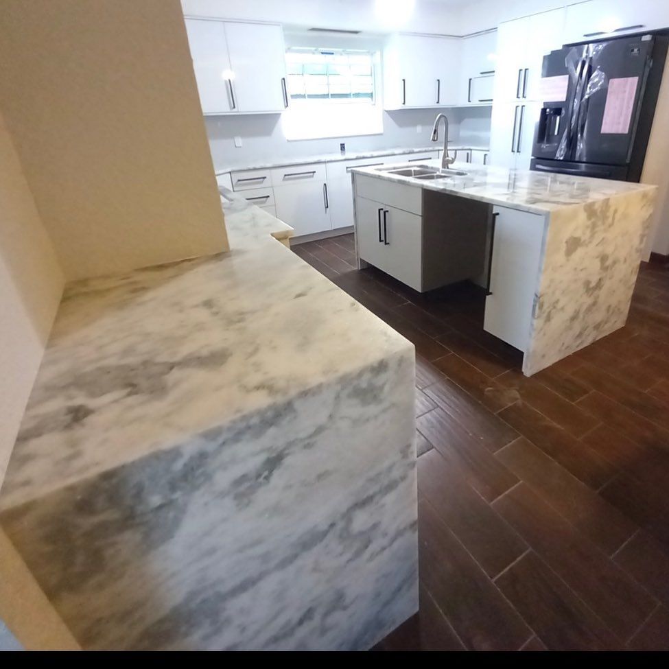 Kitchen with white cabinets, marble countertops, and dark wood floors.