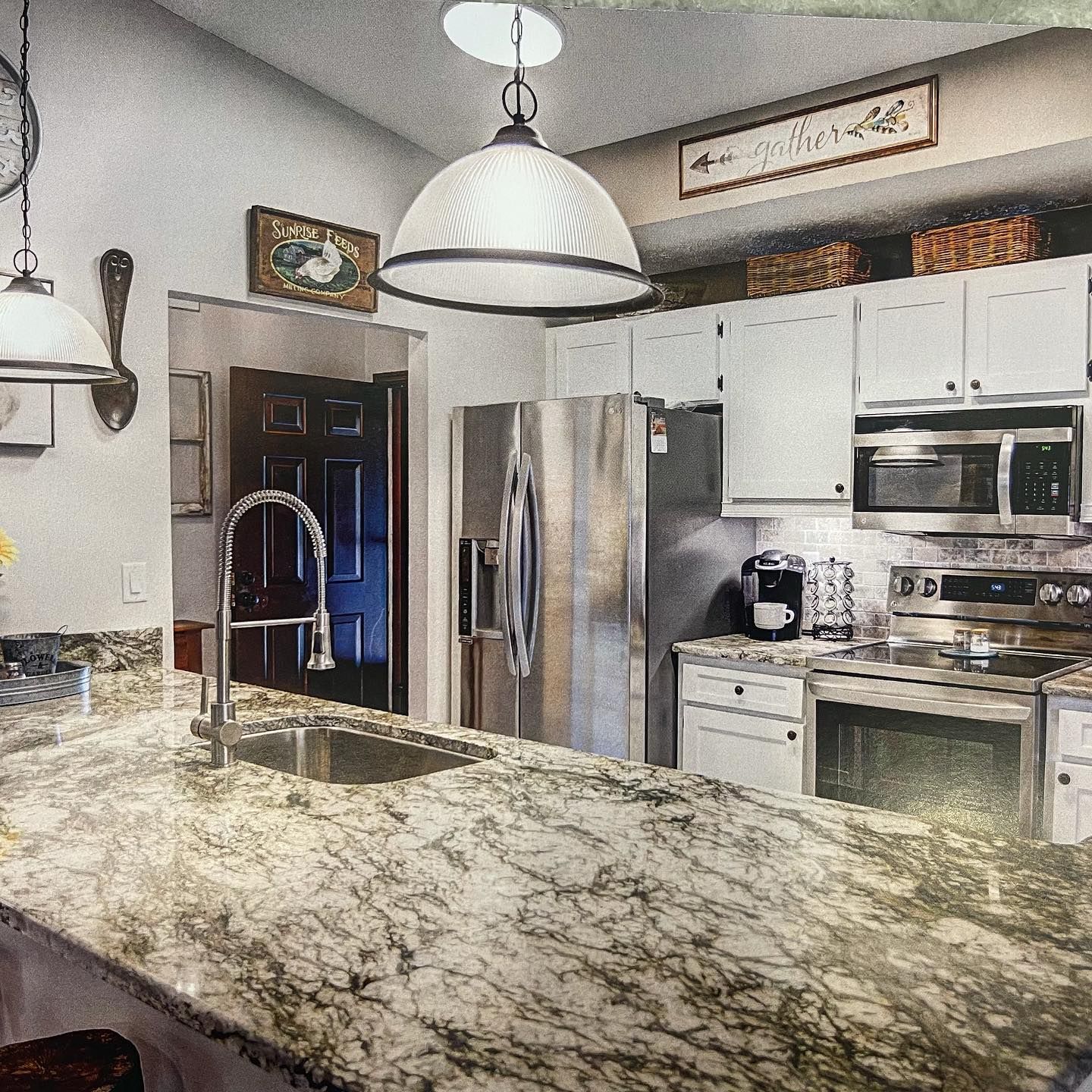 Kitchen with white cabinets, stainless steel appliances, granite countertops, and a hanging pendant light.