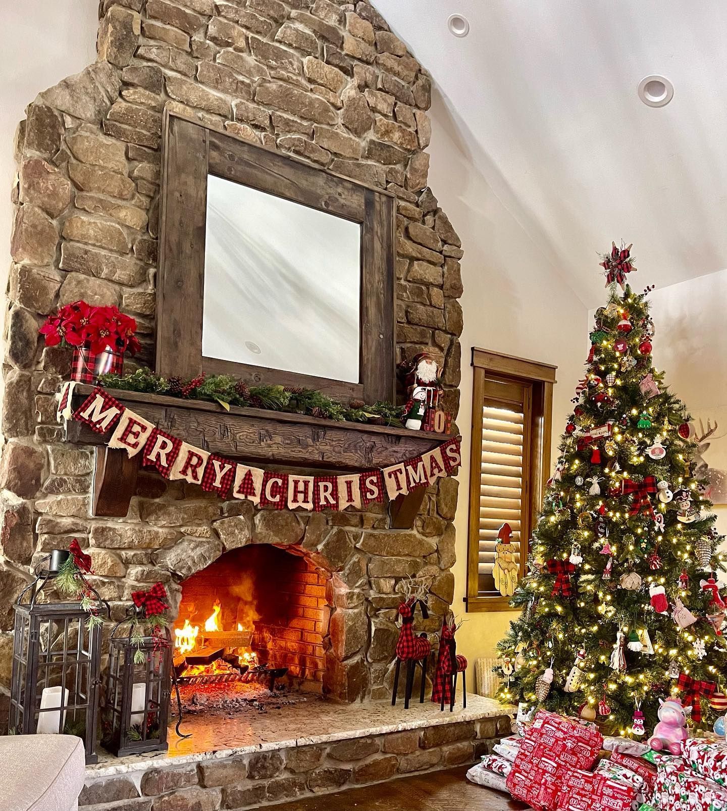 Cozy Christmas living room. Stone fireplace with lit fire, tree, gifts, and 
