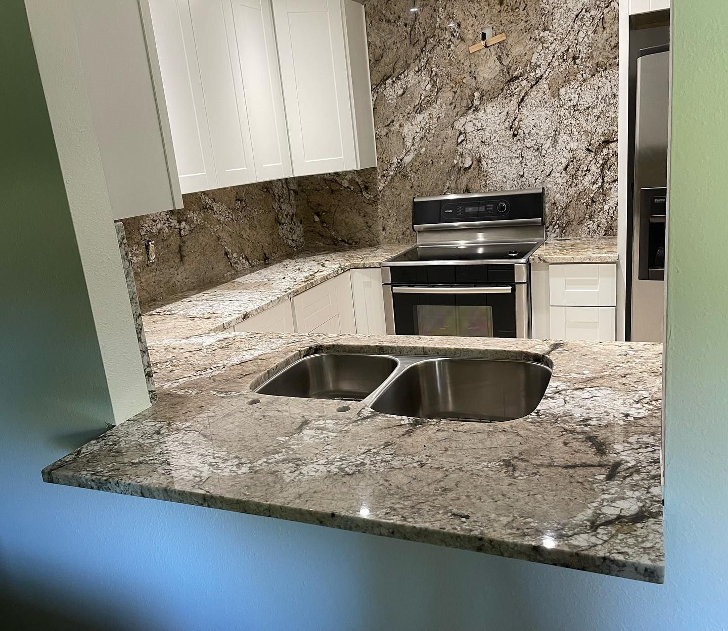 Kitchen with granite countertops, white cabinets, and stainless steel appliances.