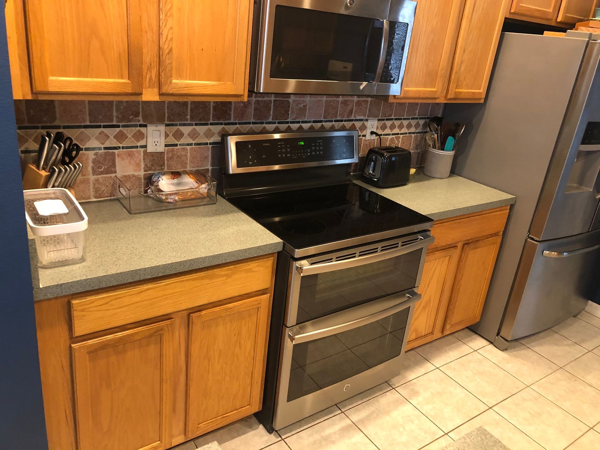 A kitchen with wooden cabinets, a stove, microwave, and refrigerator.