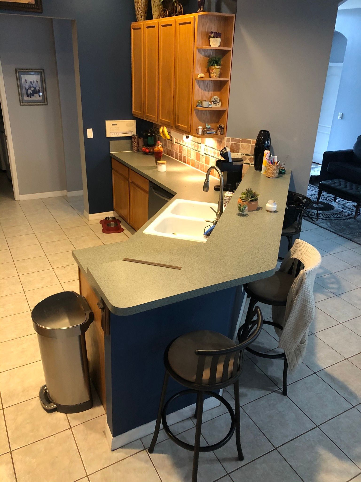 Kitchen with blue cabinets, a countertop, and two bar stools.