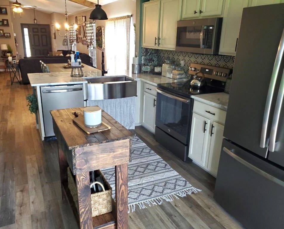 Kitchen with light green cabinets, stainless steel appliances, and a wooden island.