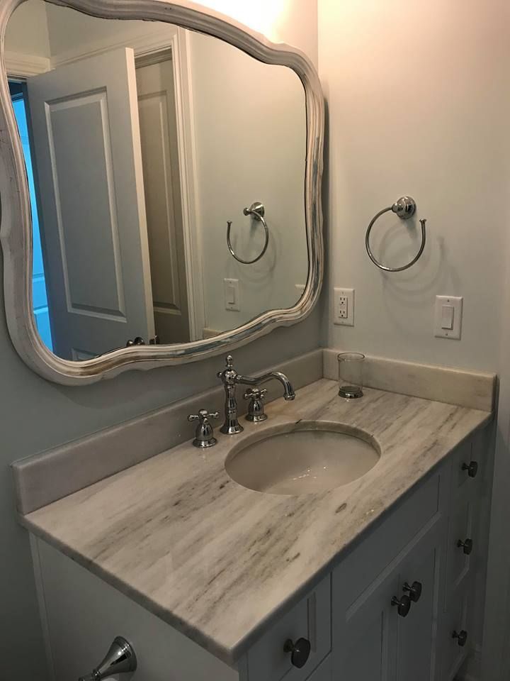 Bathroom vanity with marble countertop, oval sink, and ornate mirror.