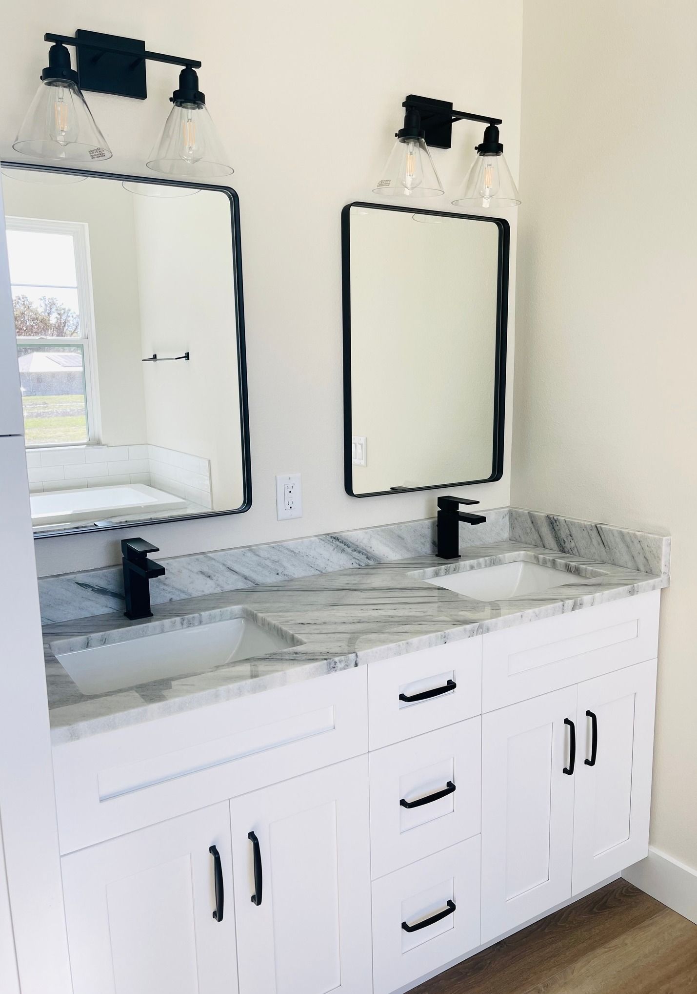 Double sink bathroom with white vanity, black fixtures, and framed mirrors.