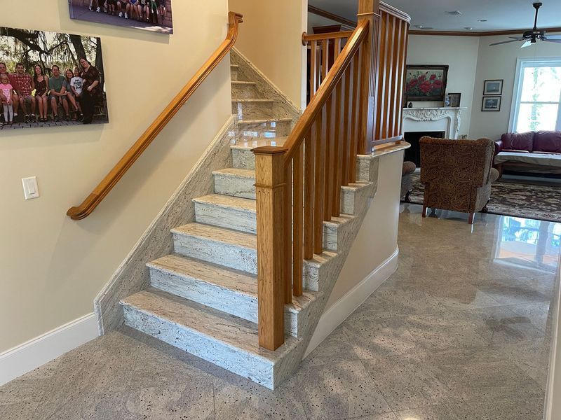 Staircase with granite steps and wooden handrails in a home's entryway.