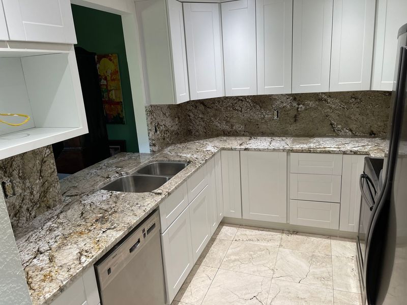 White kitchen with granite countertops, stainless steel sink and appliances.
