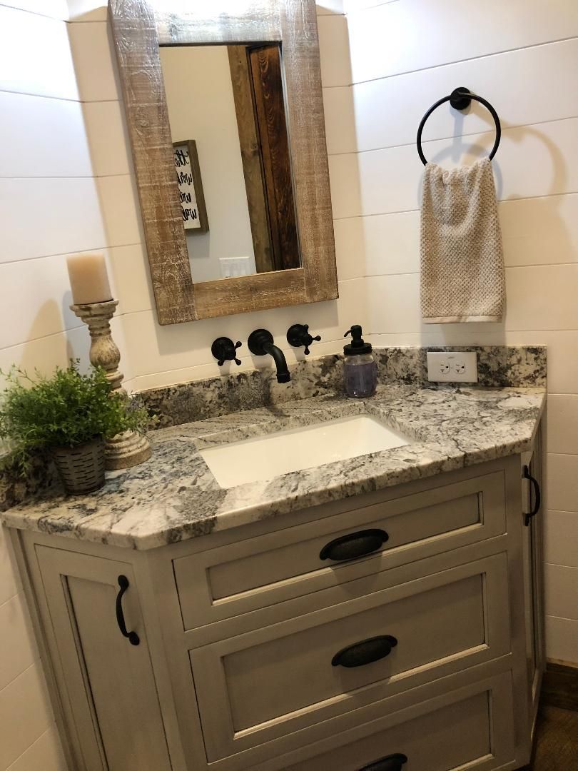 Bathroom with a vanity and mirror, featuring a gray and white countertop, black hardware, and shiplap walls.