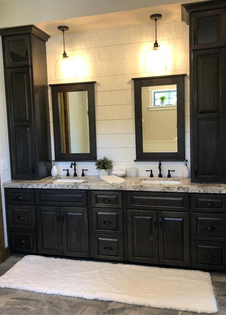 Bathroom with dark cabinets, white countertops, two mirrors, and overhead pendant lights.
