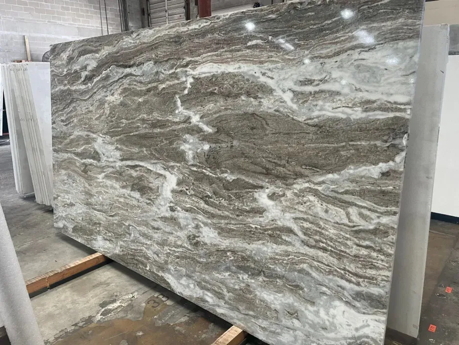 Large slab of marble with flowing brown, white, and gray veining, displayed indoors.