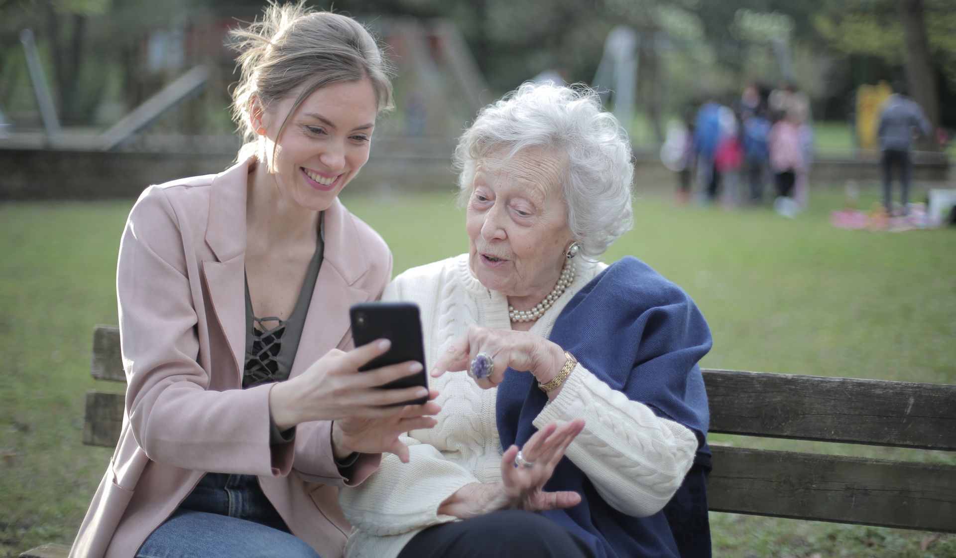 Seniorin mit Betreuerin sitzend auf einer Parkbank