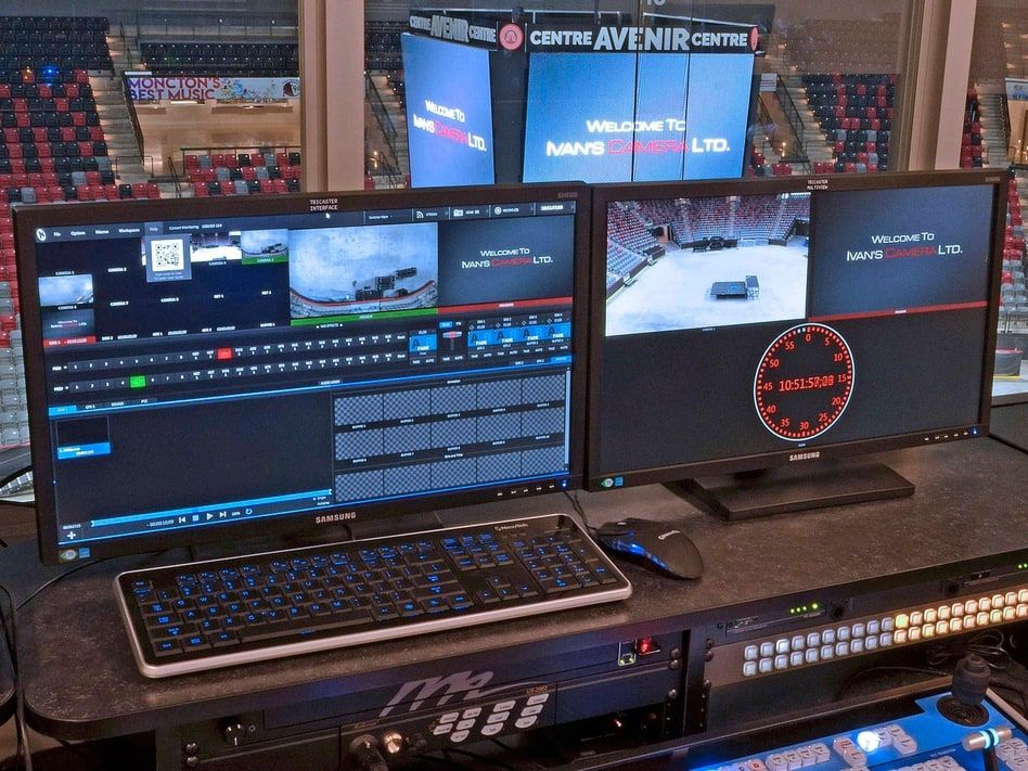 Multi-screen broadcast control desk with laptop, monitors, and video feeds in a studio control room