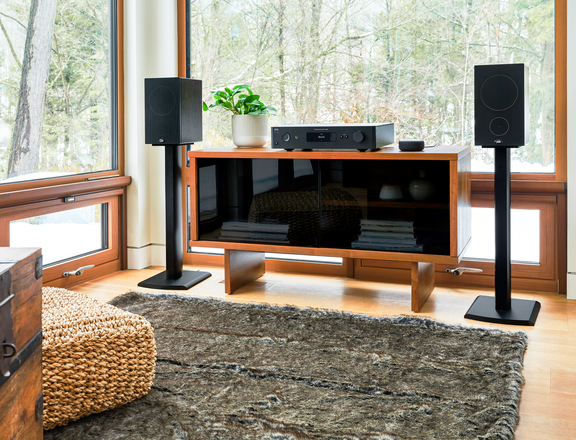 Modern living room with two speakers, a wooden media cabinet, and a rug by large windows