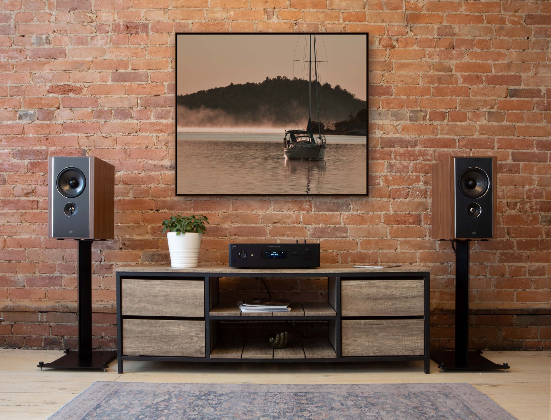 Modern living room with brick wall, framed artwork, speakers, and a low media console beneath it