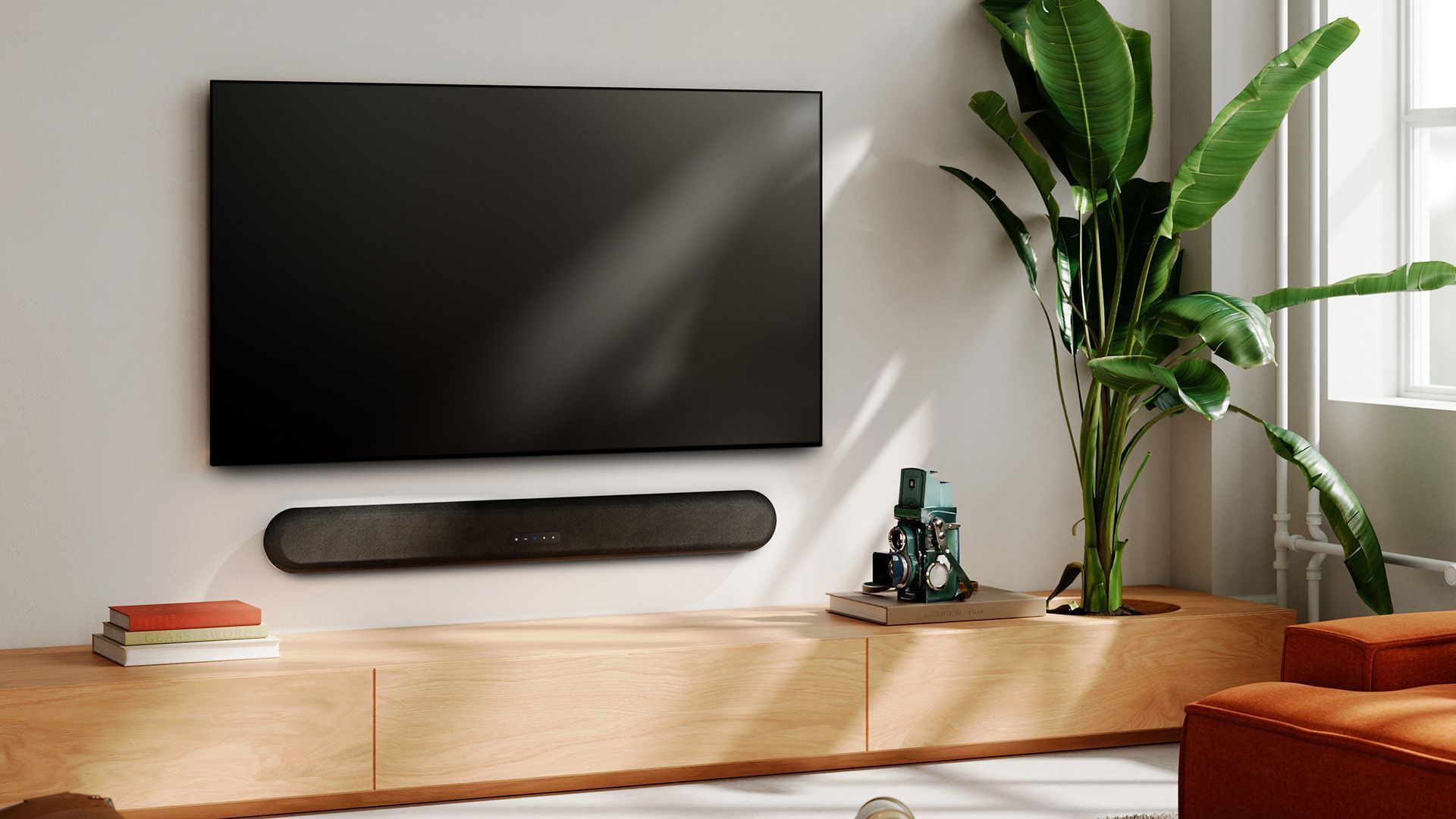 Modern living room with wall-mounted TV, soundbar, wooden console, and tall potted plant by a window