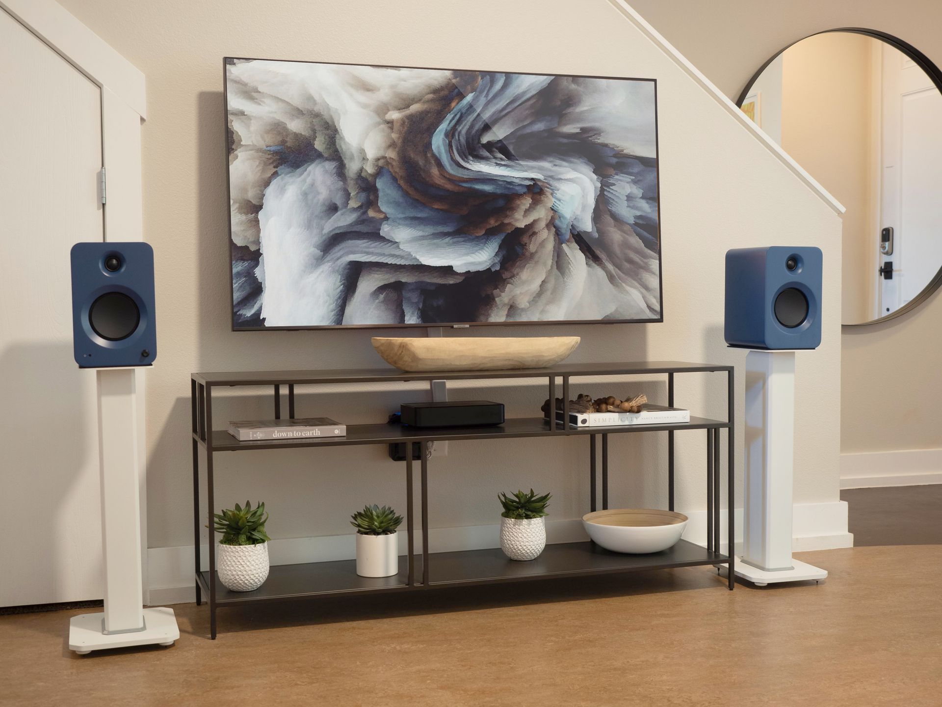 Modern living room with abstract art, blue speakers, and a TV console on a white stand