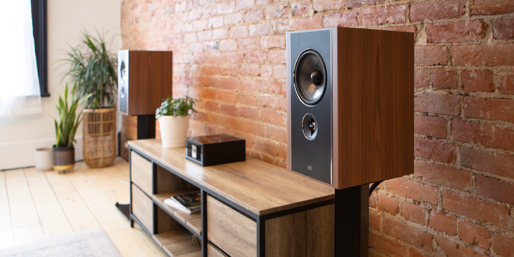 Modern living room with wooden speakers, media console, and brick wall