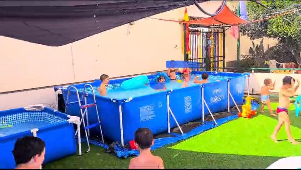 Bambini che giocano dentro e intorno alla piscina.