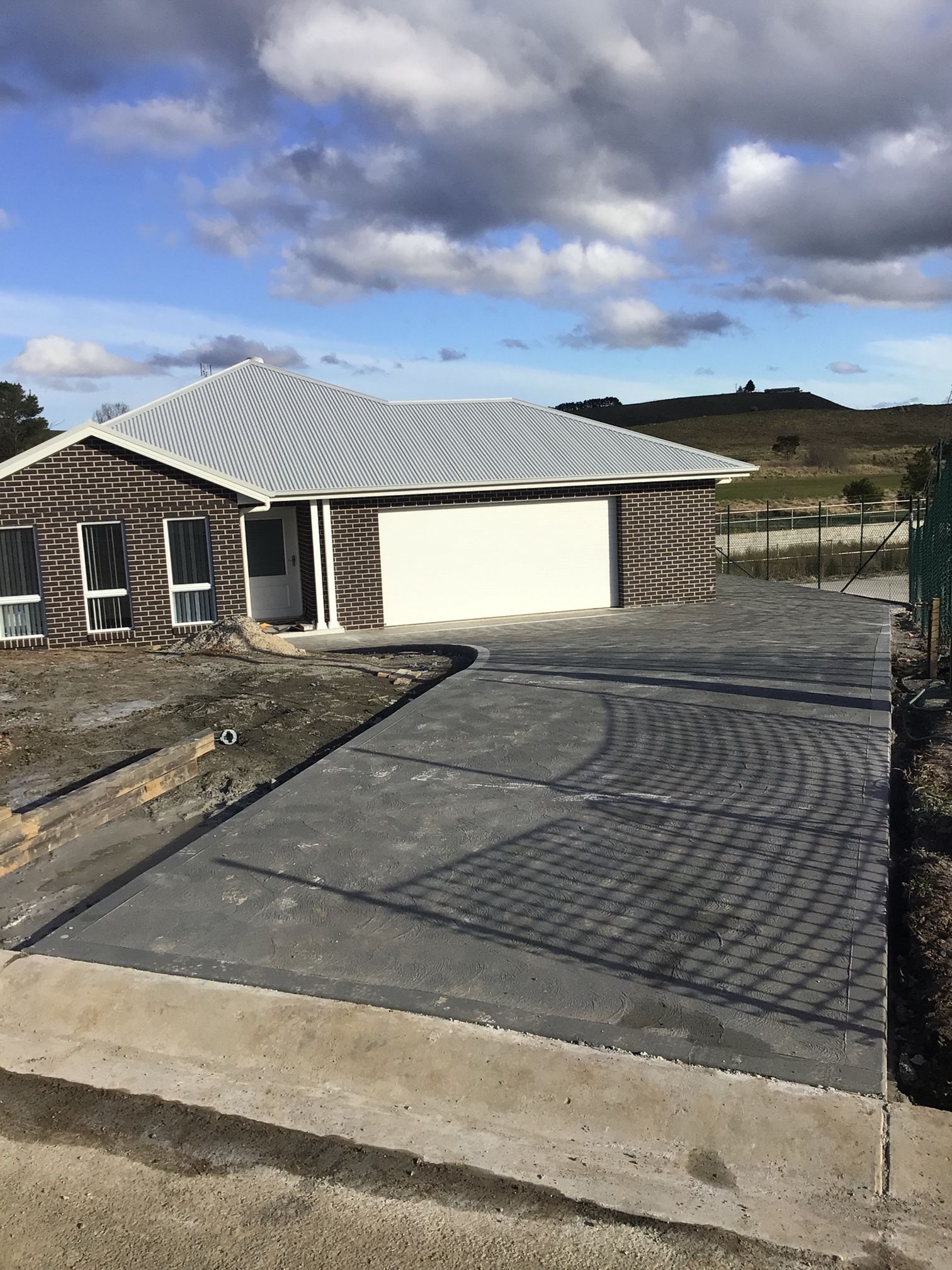 Well-maintained coal tar driveway in front of a house — About Time Plumbing & Civil Construction in Moss Vale, NSW