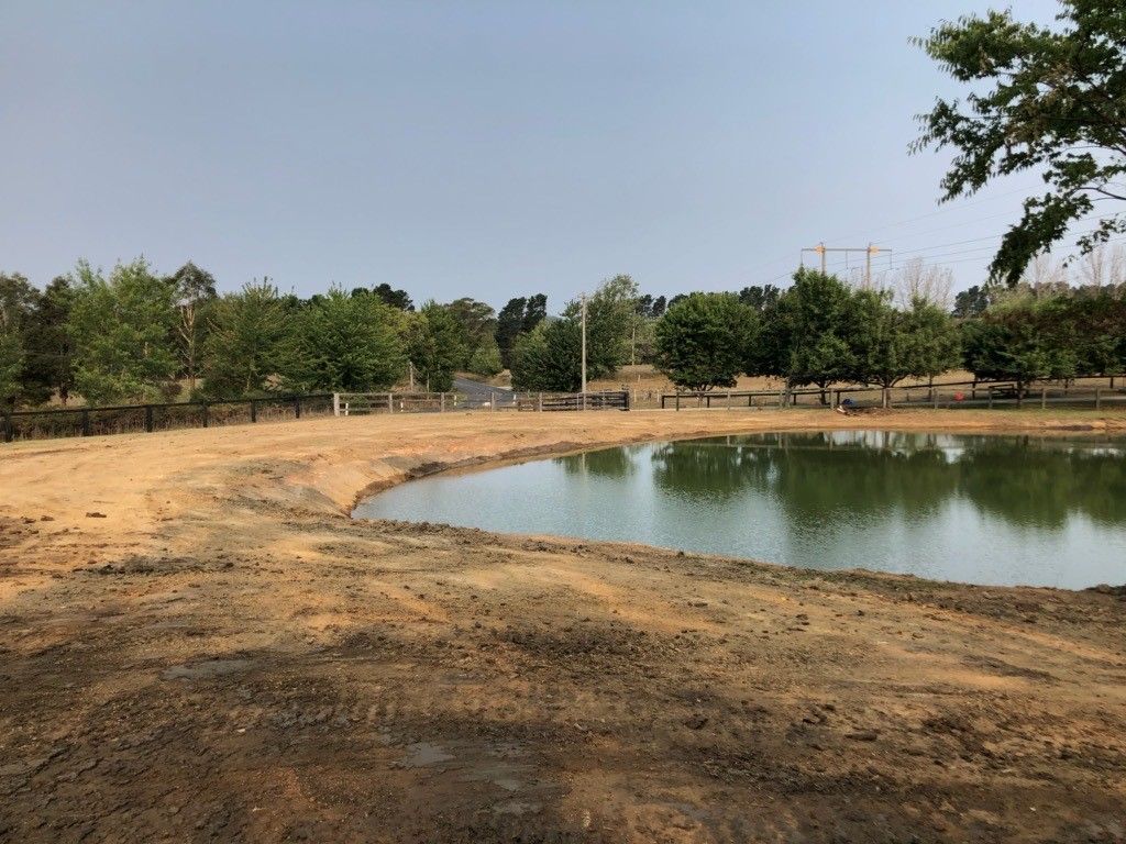 A Small Pond In The Middle Of A Dirt Field— About Time Plumbing & Civil Construction in Moss Vale, NSW
