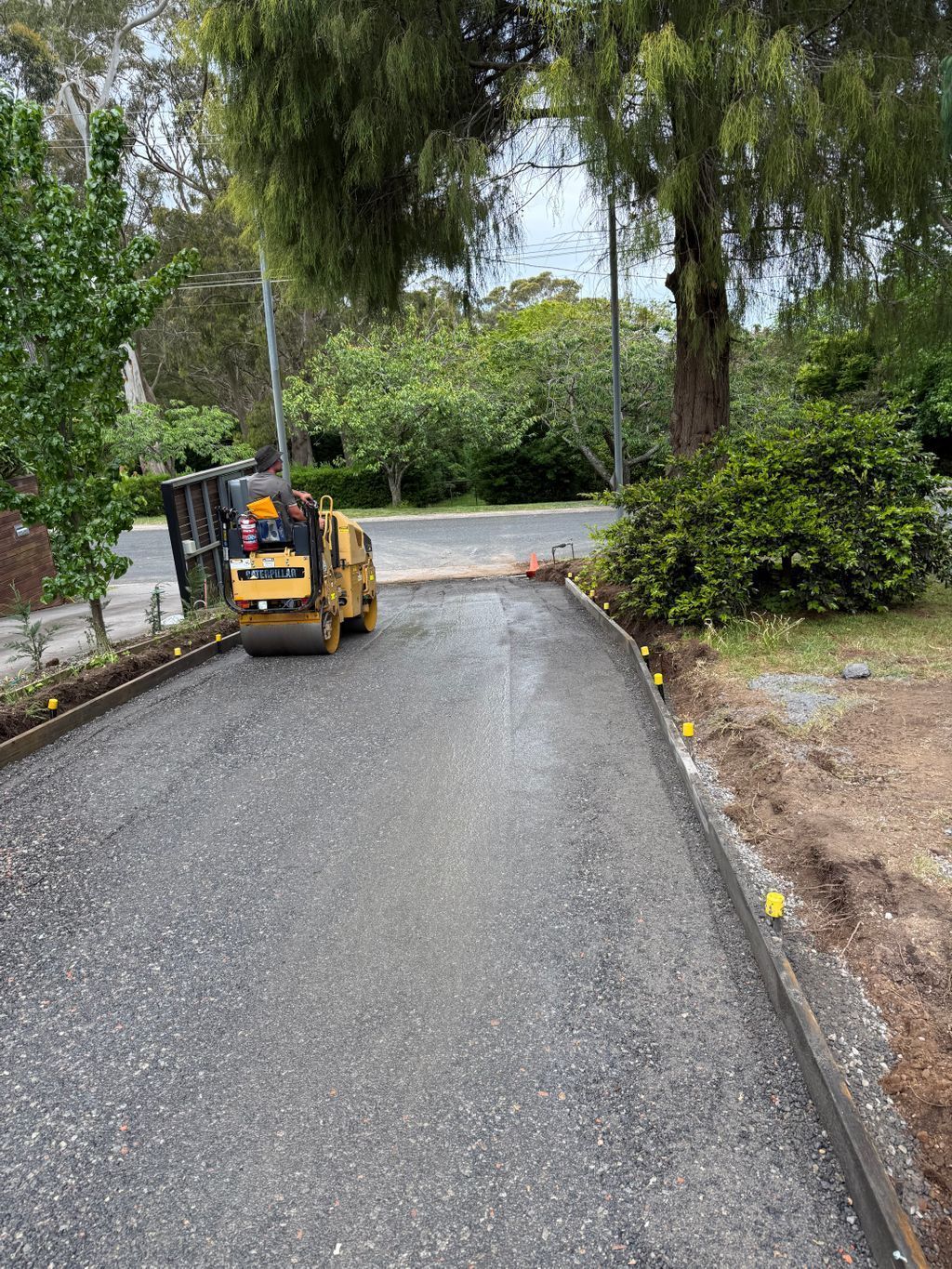A Yellow Construction Roller Compacts Gravel — About Time Plumbing & Civil Construction in Moss Vale, NSW