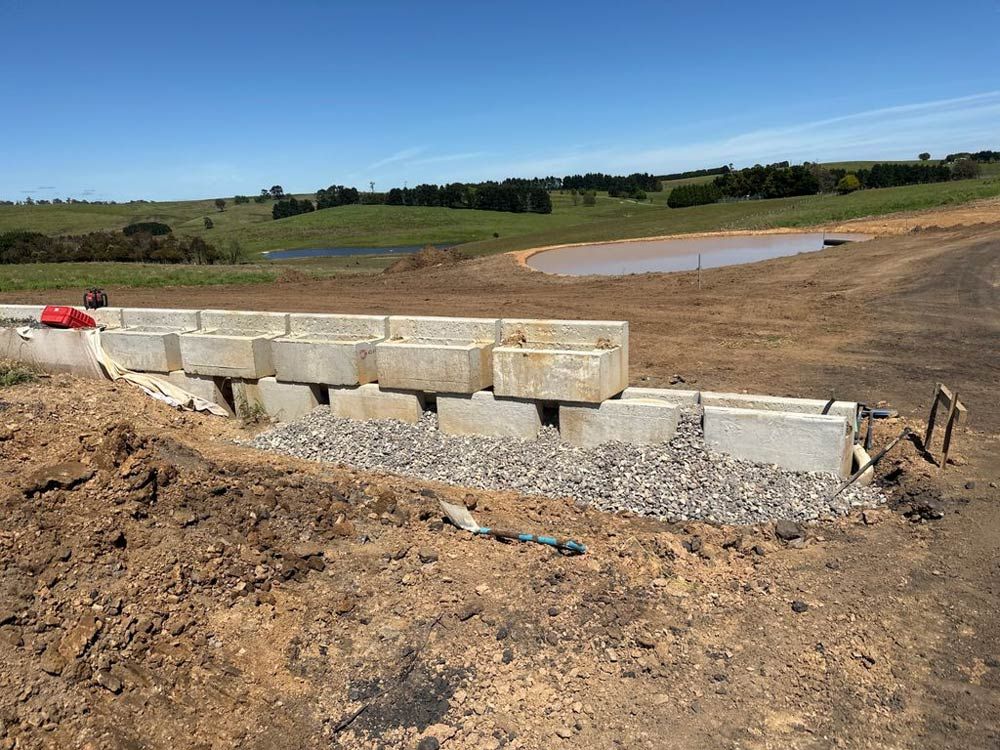 A Concrete Wall Is Being Built In A Dirt Field — About Time Plumbing & Civil Construction in Moss Vale, NSW
