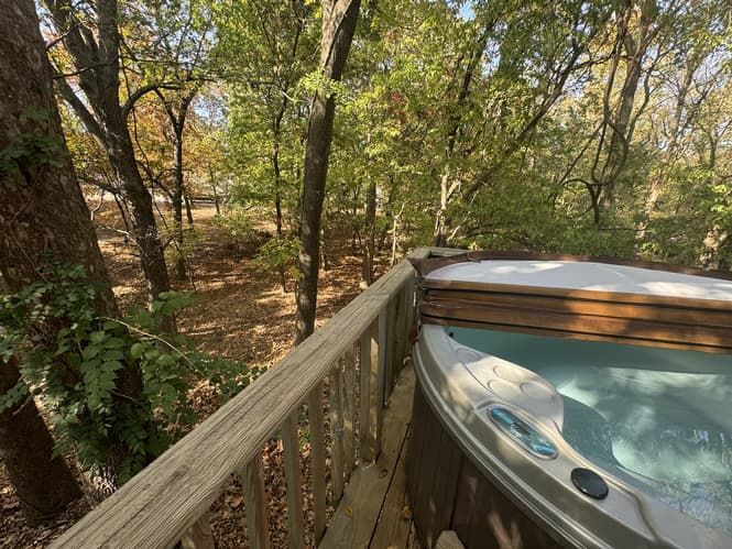 A hot tub is sitting on a wooden deck in the woods.