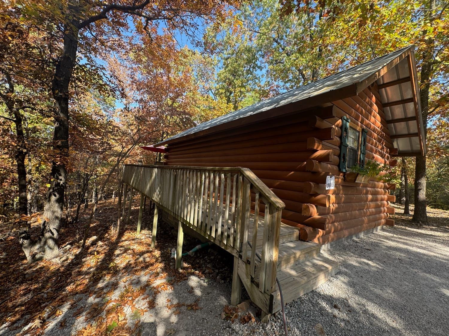 A small log cabin with a deck in the woods.
